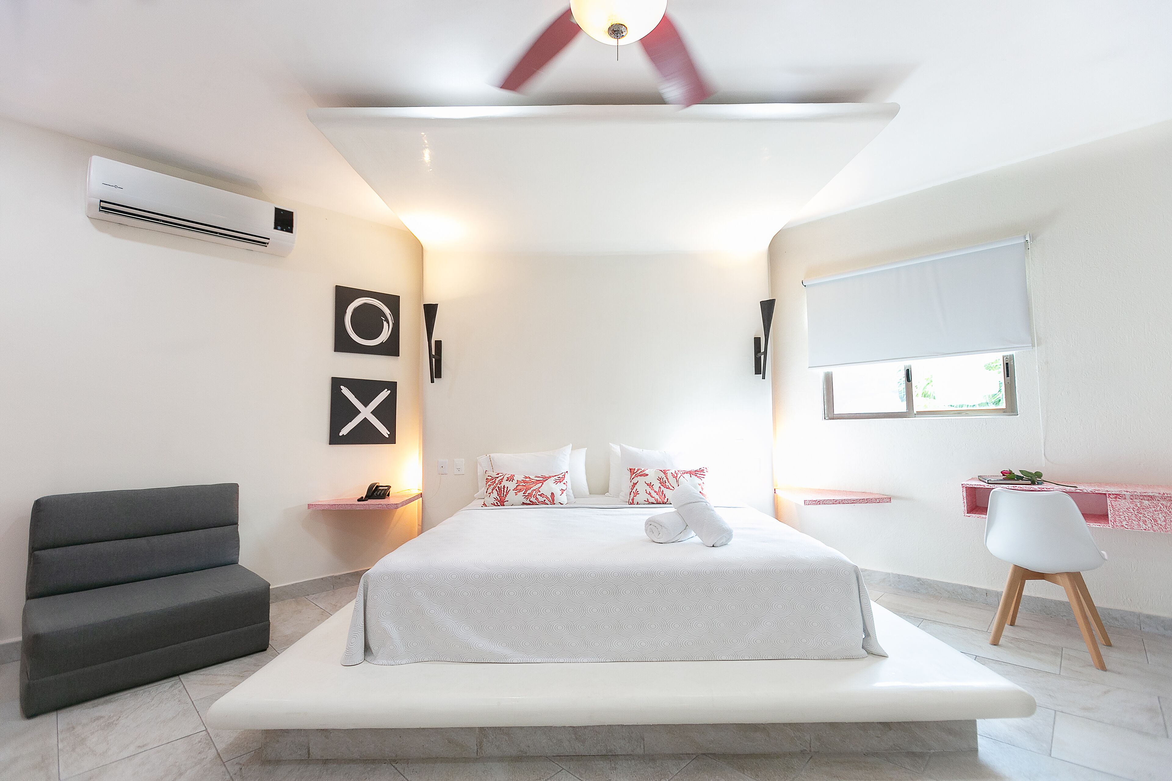 A modern bedroom with a bed, bedside tables, a desk, and a chair.