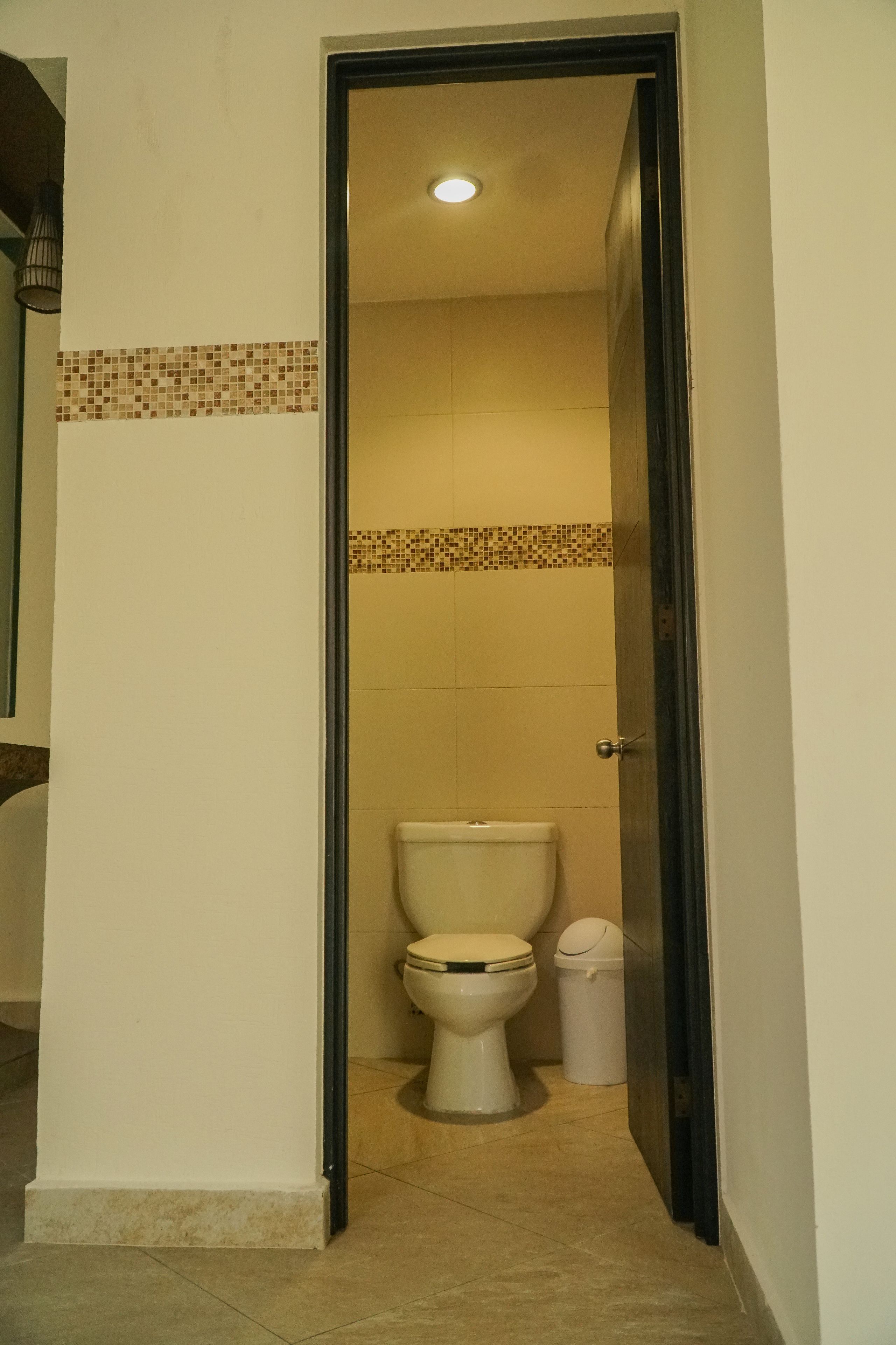 Ein schmaler Durchgang zu einem Badezimmer mit Toilette und Mülleimer.
