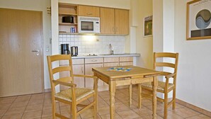 Una piccola cucina con mobili in legno, un forno a microonde e un pavimento piastrellato.