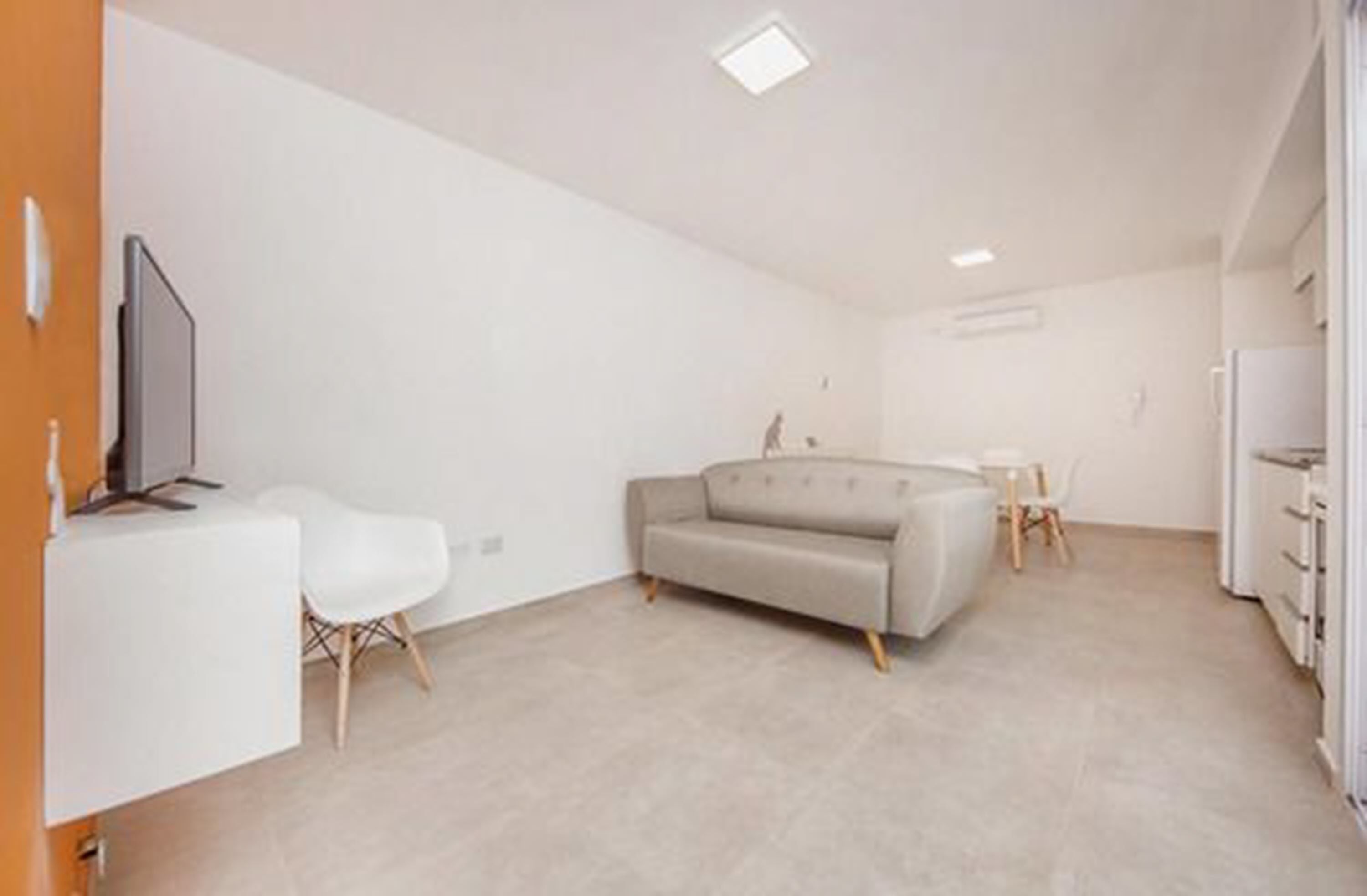 Una sala de estar moderna y minimalista con un sofá, una mesita y un televisor.