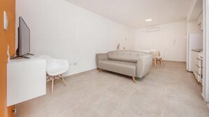 Un salon moderne et minimaliste, avec un canapé, une petite table et un téléviseur.