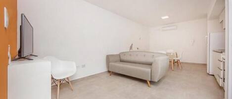 Una sala de estar moderna y minimalista con un sofá, una mesita y un televisor.
