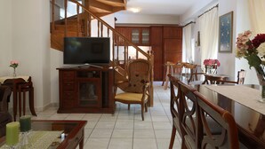 Un vaste salon agrémenté d’un escalier en bois, un coin repas et une cuisine à l’arrière-plan.