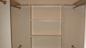 A walk-in closet with a mirrored closet rod and multiple shelves.