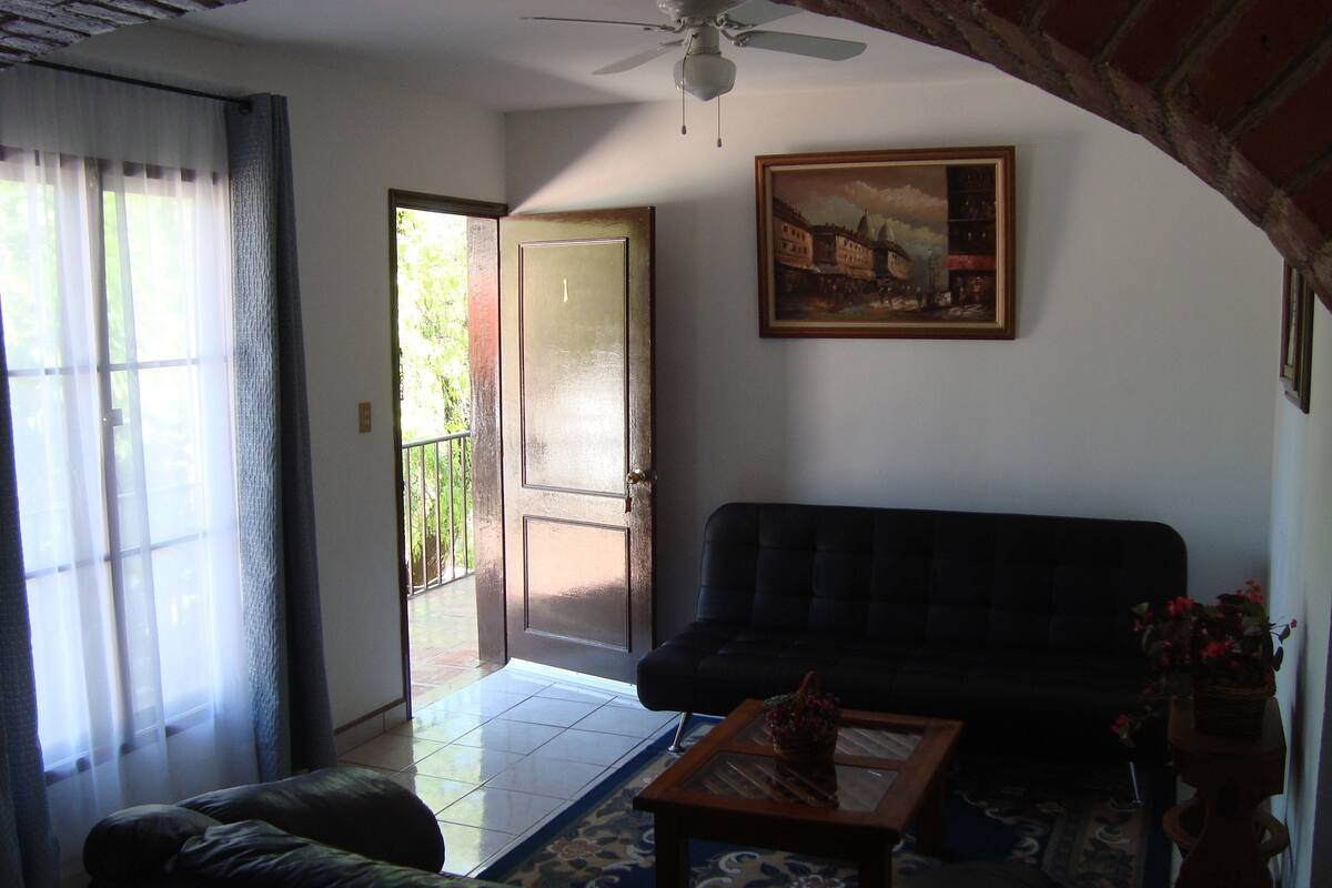 A living room with a sofa, a coffee table, and a painting on the wall.