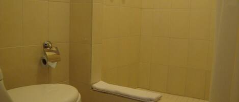 A bathroom with a toilet, a towel rack, and a shower area.