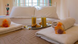 A neatly made bed with two towels, a tray with pastries and juice glasses, and a nutcracker figurine on the side. - Heart of the old town (Corfu)