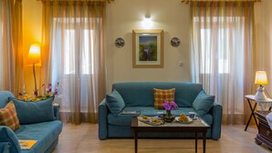 A living room with a teal sofa, a coffee table with a tray of pastries, and a lamp. - Heart of the old town (Corfu)