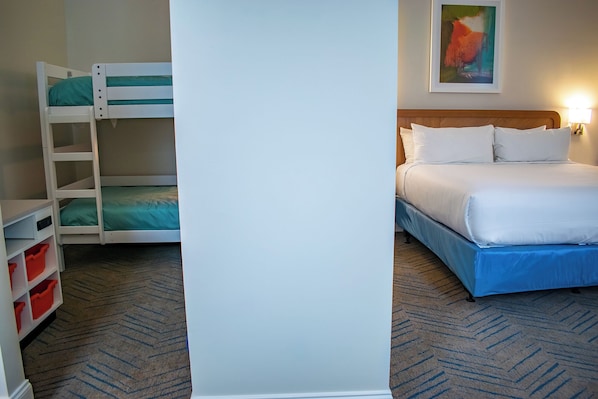 A hotel room with bunk beds, a single bed, and a carpeted floor.