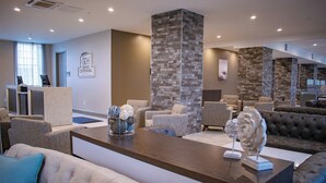 A lobby with a reception desk, seating area, and a stone accent wall. - Centennial Plaza Resort Gulfport (Gulfport)