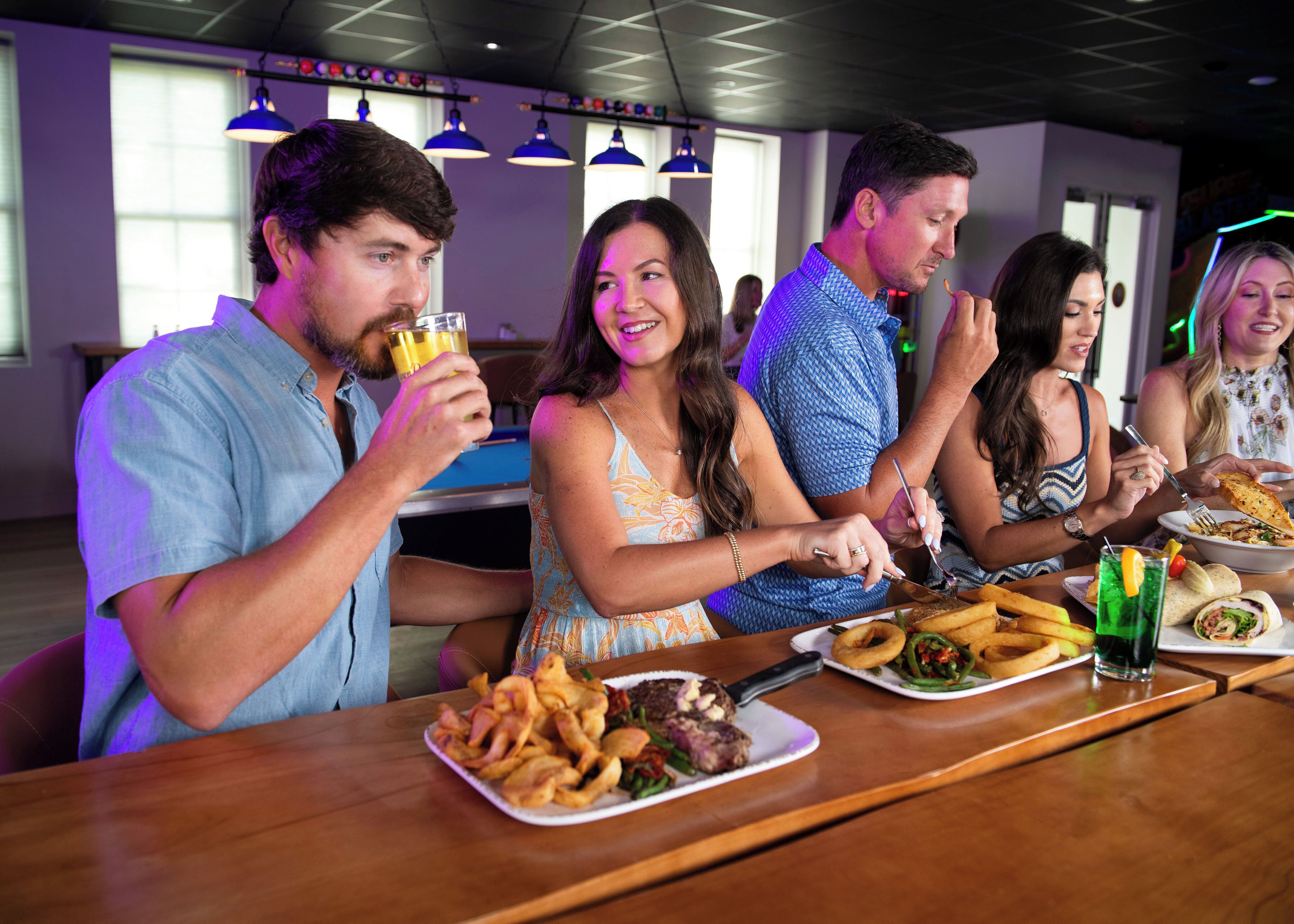 A group of people dining at a restaurant with a variety of dishes on the table, including fried food and a fish dish.