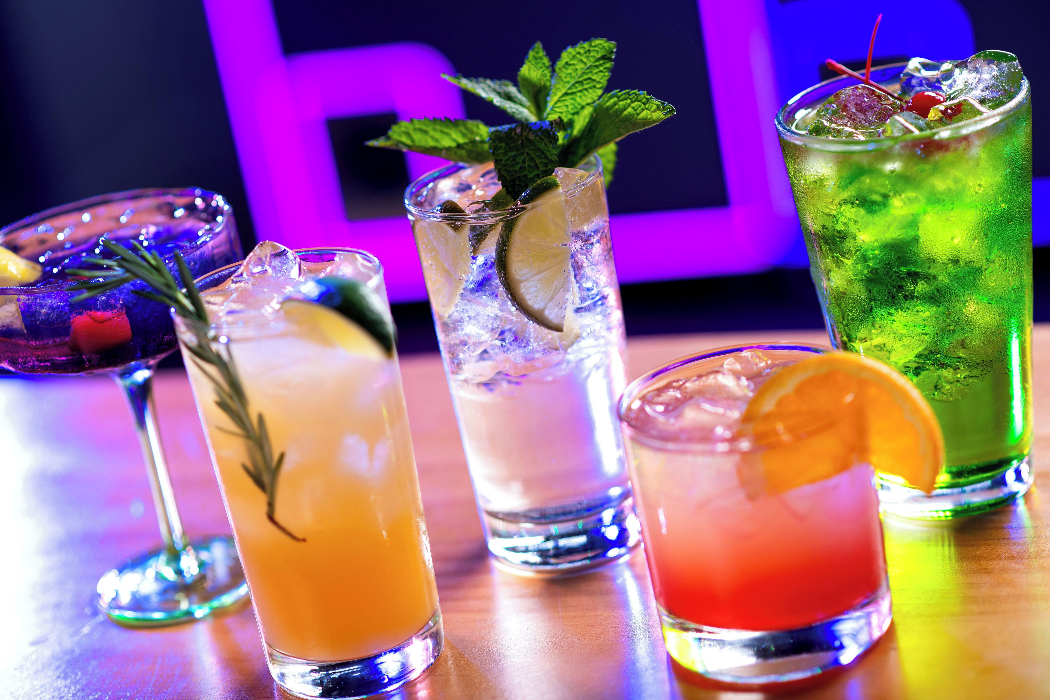 Une variété de cocktails colorés présentés sur le comptoir d’un bar.