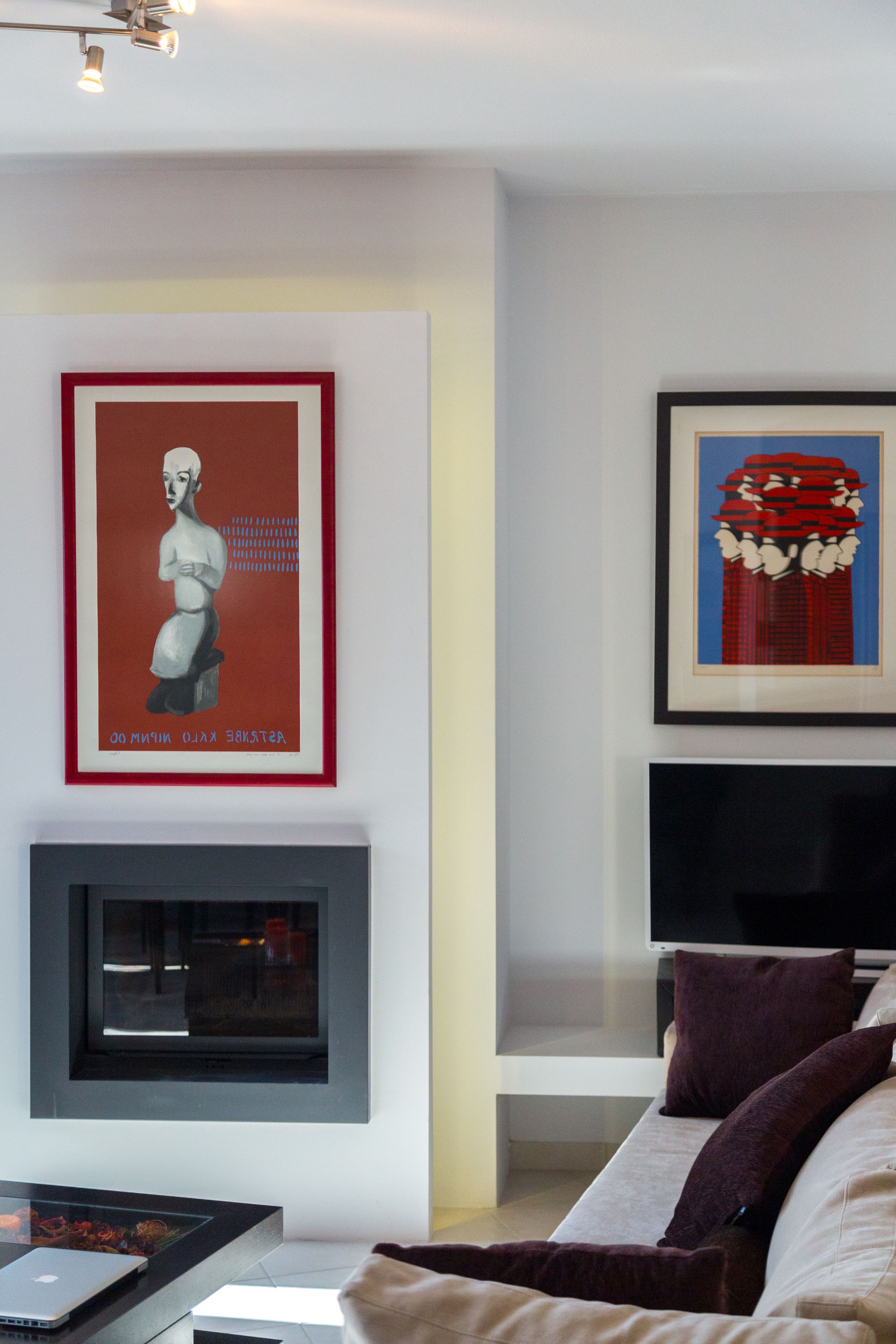Ein modernes Wohnzimmer mit Flachbildfernseher, Kamin und zwei gerahmten Kunstwerken an der Wand.