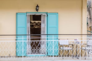 A balcony with turquoise shutters, a white metal railing, and a small table with chairs. - Casa Voula (Corfu)