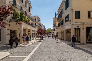 Eine gepflasterte Straße gesäumt von historischen Gebäuden, einige davon mit Balkonen und Beschilderung.