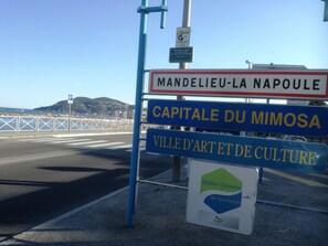 A signpost with multiple destination names including 'Mandelieu-La Napoule', 'Capitale Du Mimosa', and 'Ville d'Art et de Culture'.