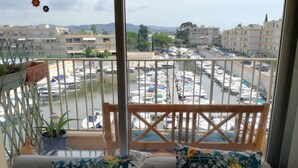 A balcony with a view of a marina, a wooden railing, and a sofa with patterned cushions.