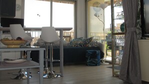 A modern living room with a dining area, large windows, and a view of the outdoors.