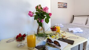 A breakfast setup with a vase of pink roses, a bowl of strawberries, a glass of orange juice, and a glass of water on a table. - Foxy Studio 2 (Corfu)
