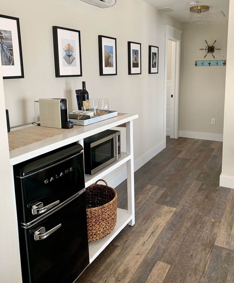 A kitchen area with a microwave, oven, and a black dishwasher. There are framed pictures on the wall and a basket on the counter.