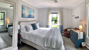 Un dormitorio con una cama grande, un aparador, un espejo y un cuadro de veleros.