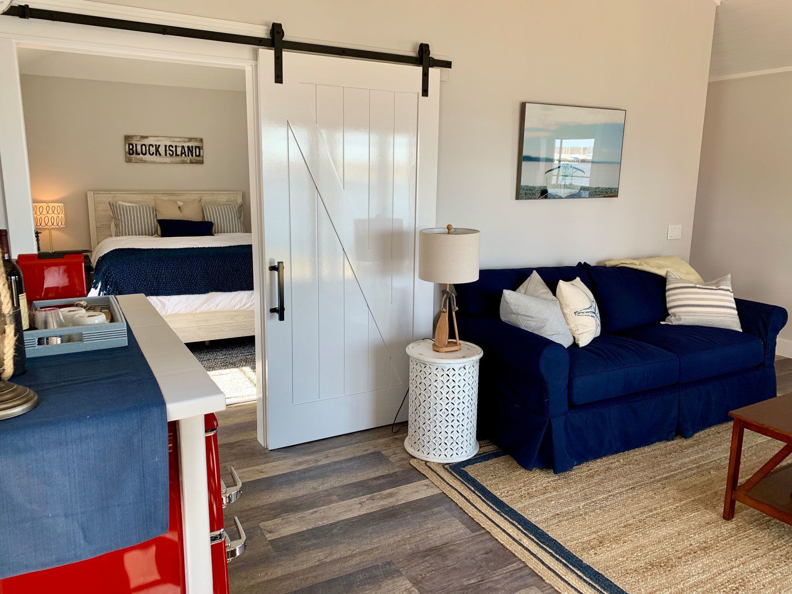 Une pièce avec un lit, un canapé bleu, une lampe, une petite table et un panneau sur lequel on peut lire « BLOCK ISLAND ».