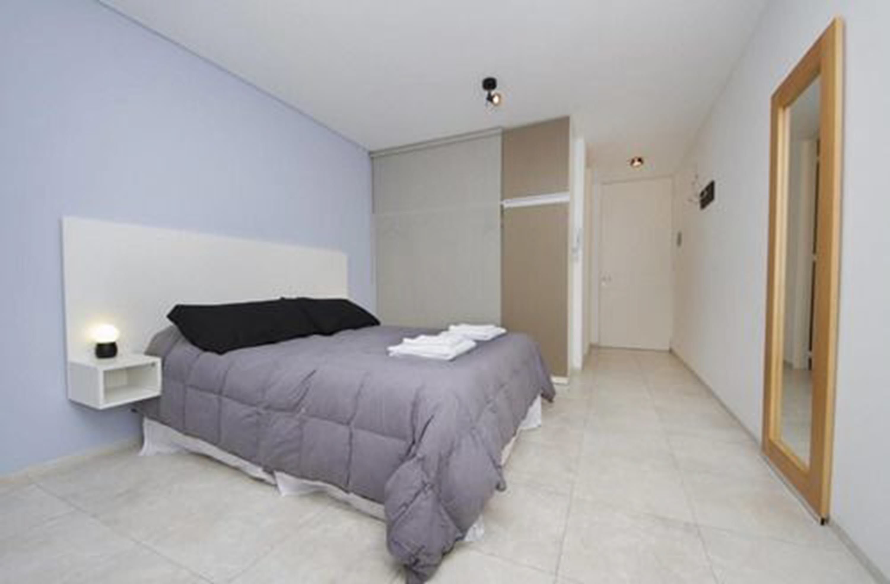 A bedroom with a bed, bedside table, and a wardrobe.