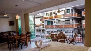 Habitación de hotel con balcón, comedor y cama con toalla en forma de corazón.