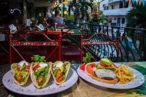 Un restaurante con terraza, que incluye sillas metálicas rojas con la inscripción 