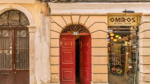 En butiksfacade med en røddør og et skilt, der siger "OMIROS GIFT SHOP - SOUVENIR".