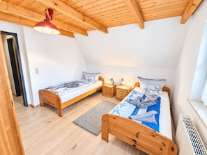 Un dormitorio con dos camas de madera, una lámpara de techo roja y un ventanal con vistas.