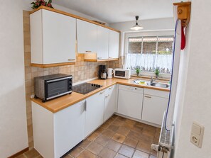 A compact kitchen with white cabinets, a microwave, a toaster, and a sink.