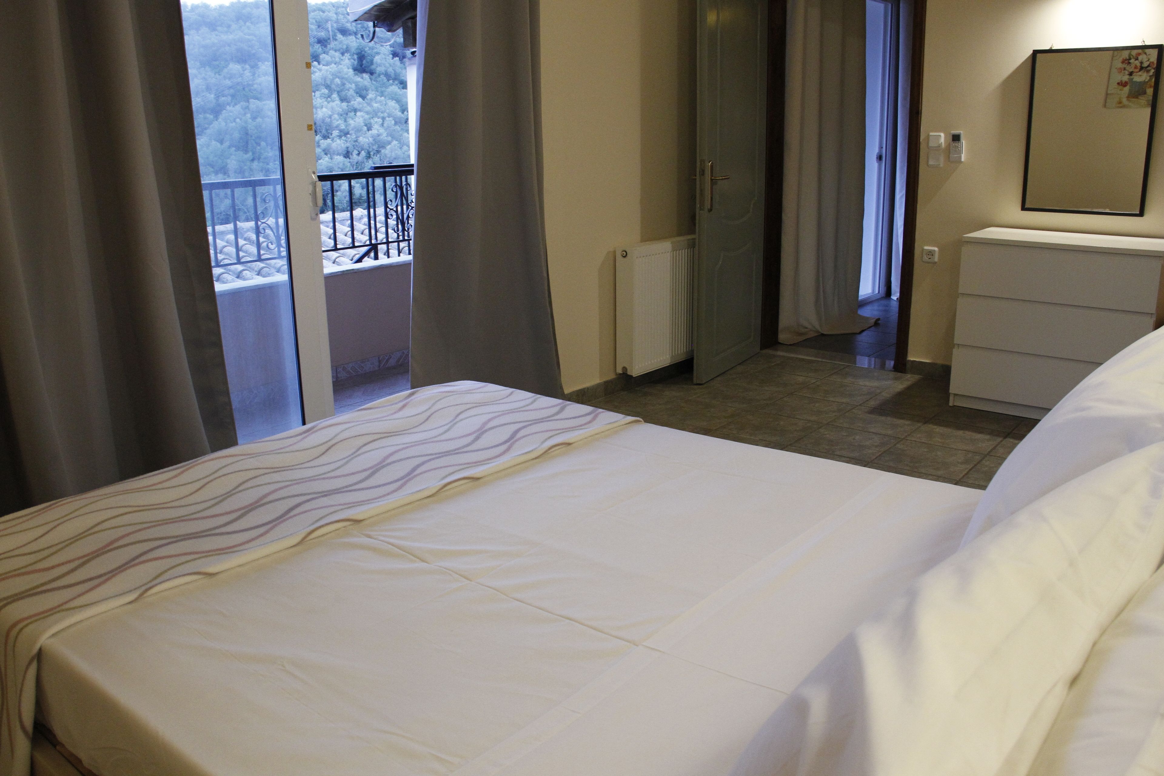 A hotel room with a bed, a dresser, a radiator, and a view of a snowy balcony.