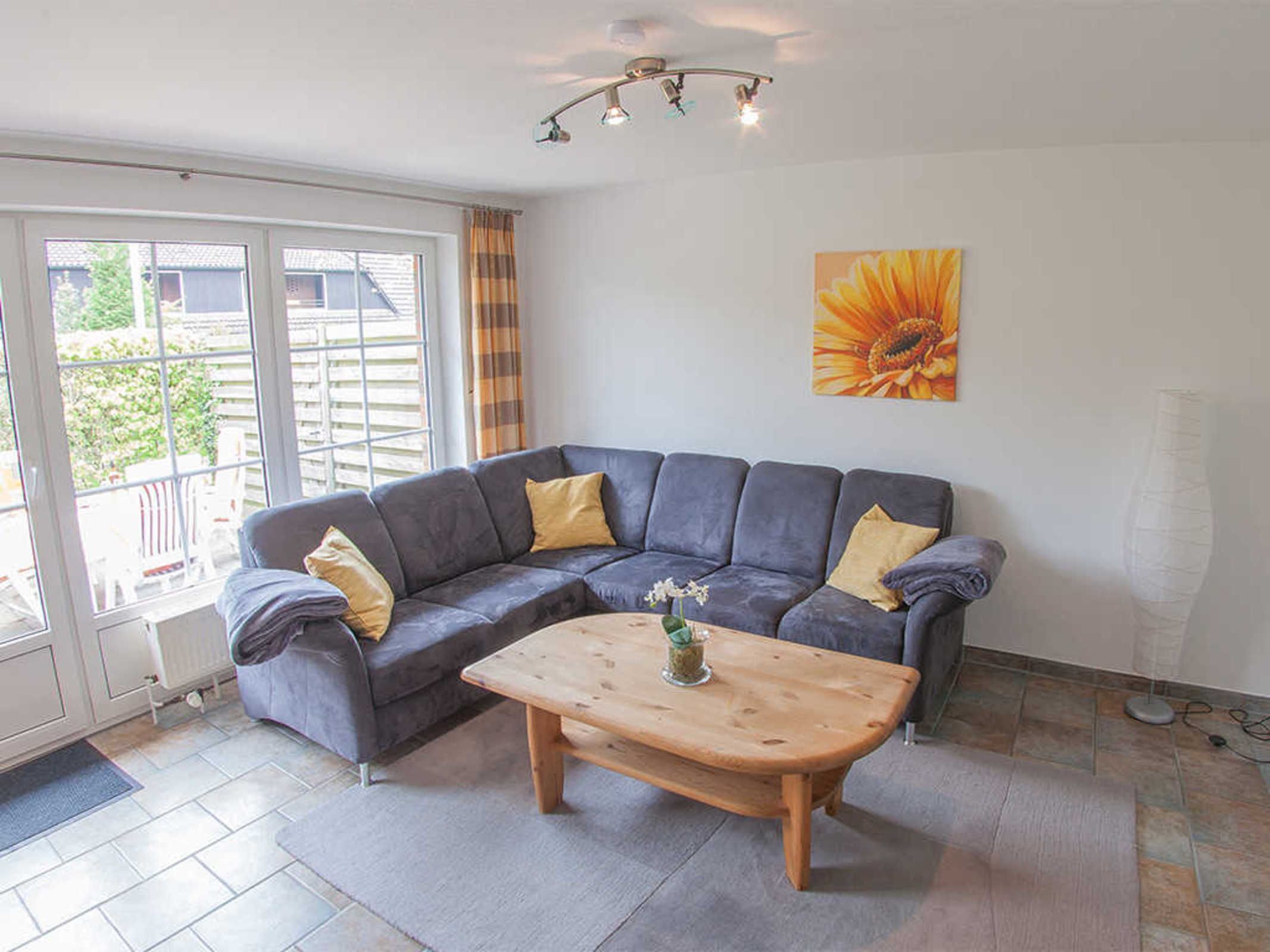 A living room with a grey sofa, wooden coffee table, and a large window with curtains.
