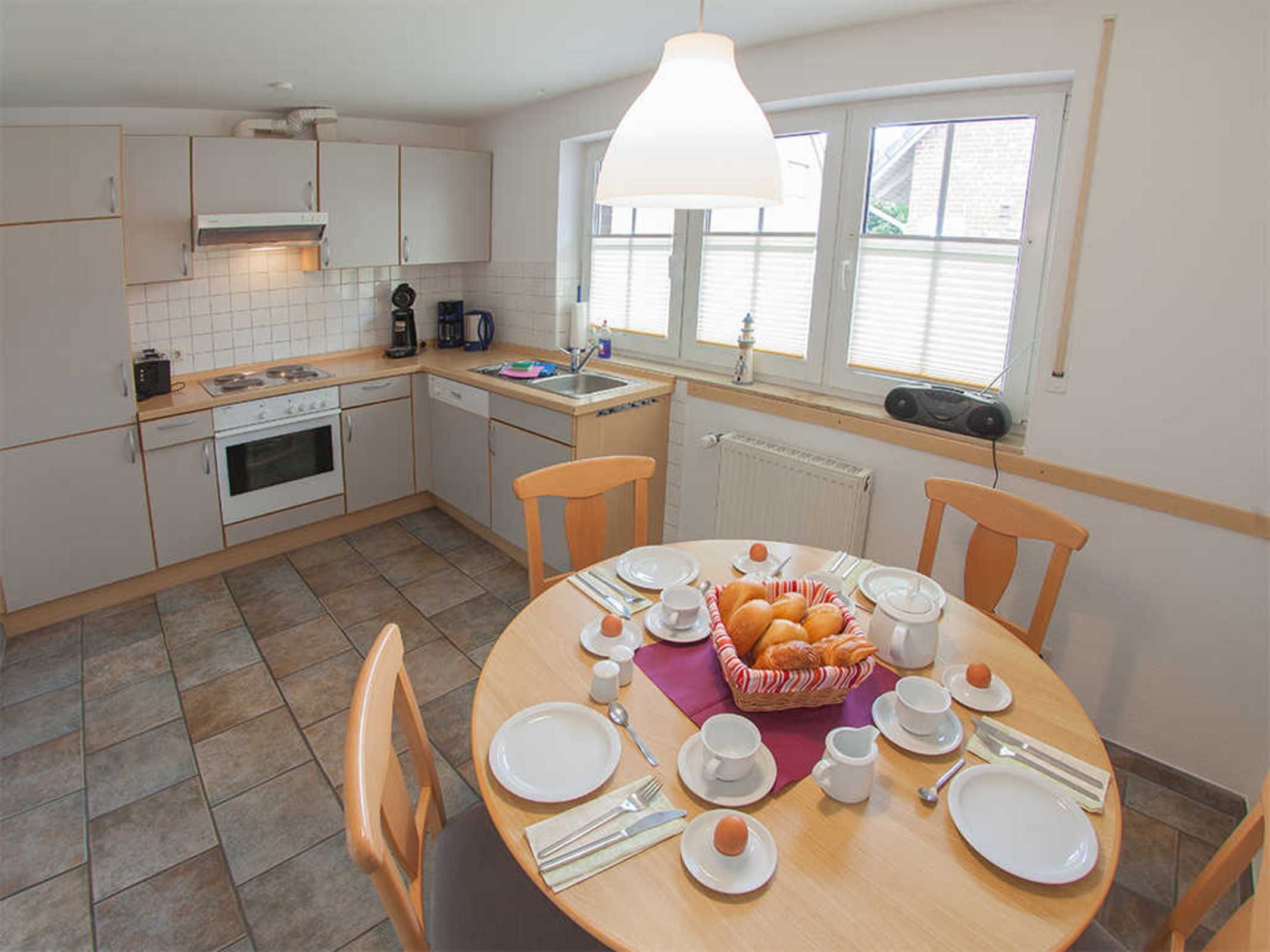 A kitchen with a dining table set for breakfast, including bread, eggs, and coffee.
