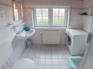 A small, clean bathroom with a sink, toilet, and washing machine. - Vacation home lighthouse, holiday apartment rental North Sea - vacation home lighthouse (Varel)