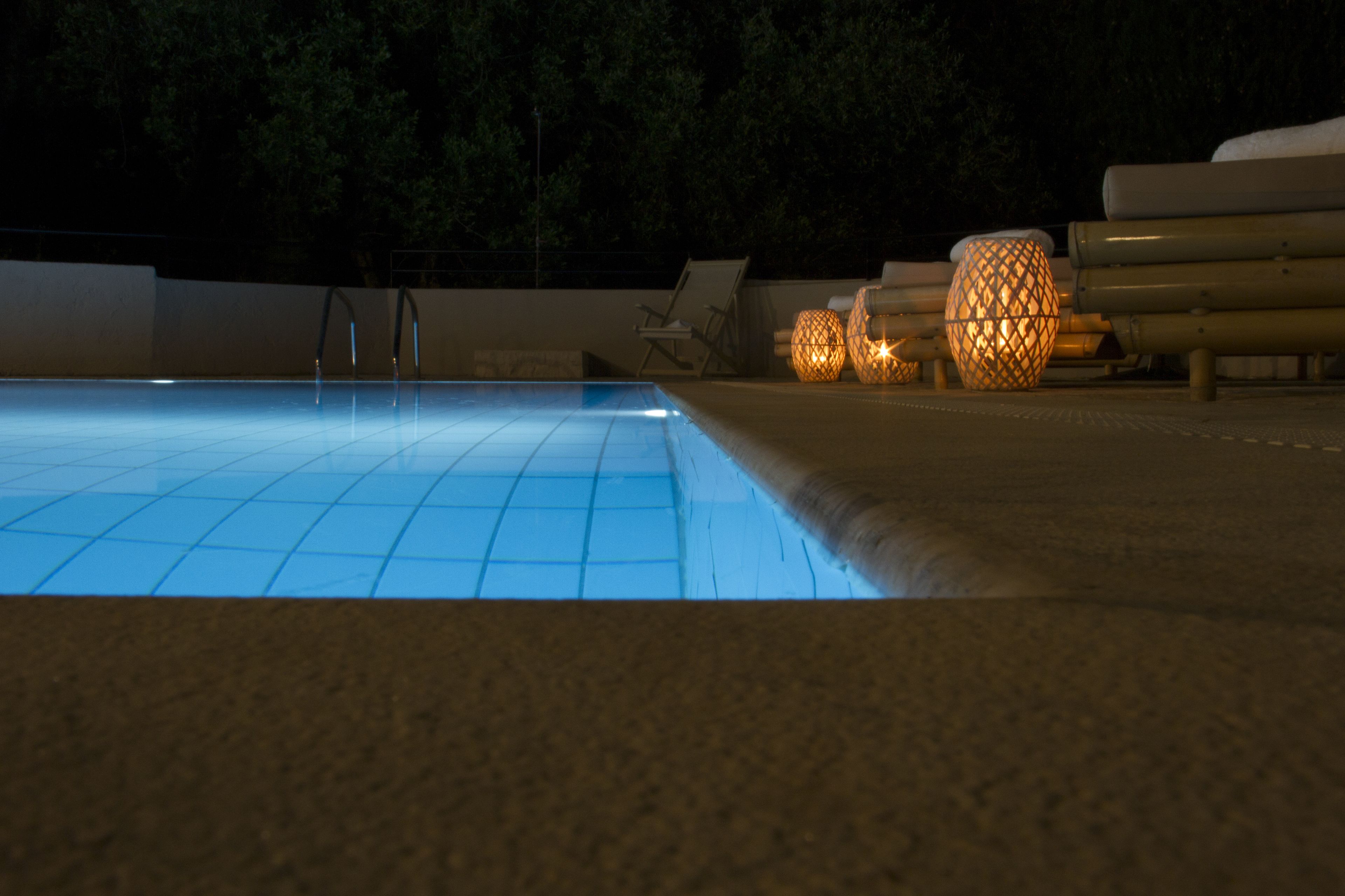 A swimming pool with a tiled edge, lounge chairs, and decorative lanterns.