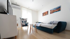 Una sala de estar moderna con un sofá azul, un escritorio blanco y un sillón estampado.