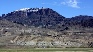 A mountainous landscape with a prominent peak covered in snow. - Rand Creek Ranch (Cody)
