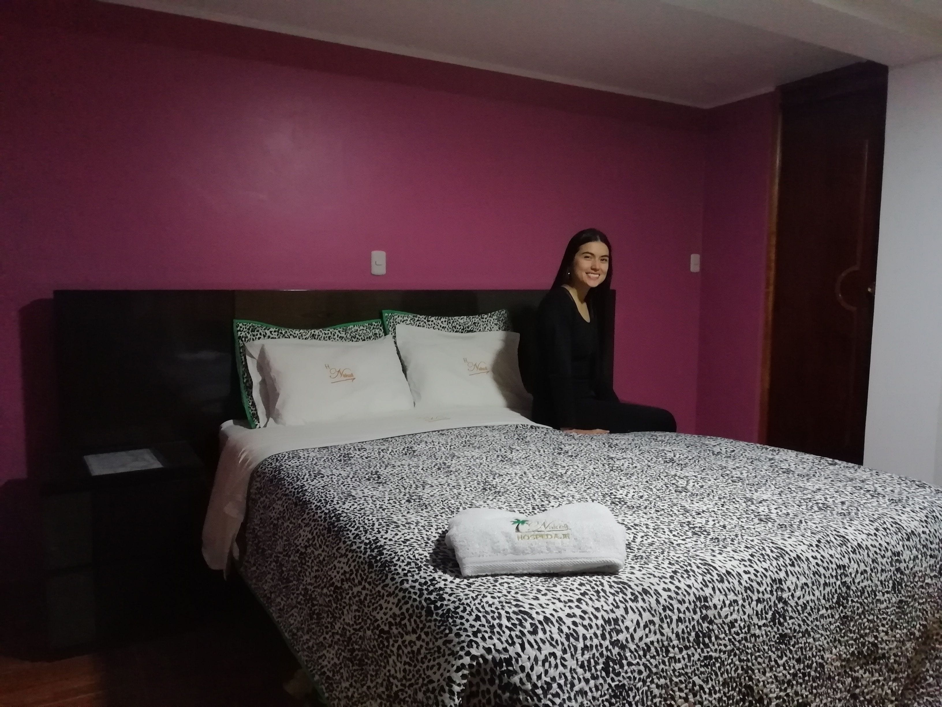 A room with a bed, a nightstand, and a door.