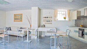 Une cuisine moderne avec un coin repas, comprenant une table blanche, des chaises et une fenêtre avec des rideaux.