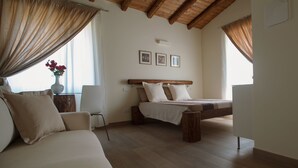 Une chambre à coucher avec un lit en bois, un canapé et une chaise. Trois tableaux encadrés sont accrochés au mur.