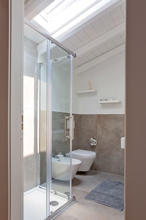 Une salle de bain moderne avec une douche à parois de verre, une baignoire sur pieds et des toilettes.