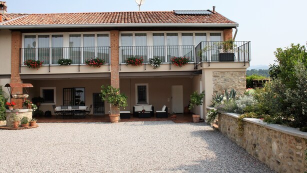 Un bâtiment à deux étages, doté d’un toit en tuiles, de balcons avec des garde-corps et de plantes en pot.
