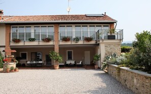 Un bâtiment à deux étages, doté d’un toit en tuiles, de balcons avec des garde-corps et de plantes en pot.
