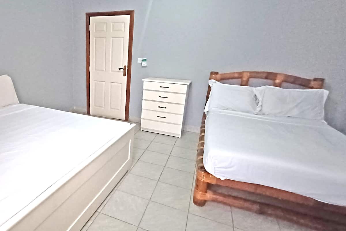 Un dormitorio con dos camas, un aparador blanco y una puerta.