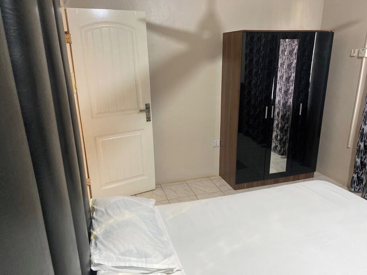 A bedroom with a bed, a wardrobe, and a door.