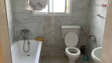 Een badkamer met een bad, toilet en wastafel.
