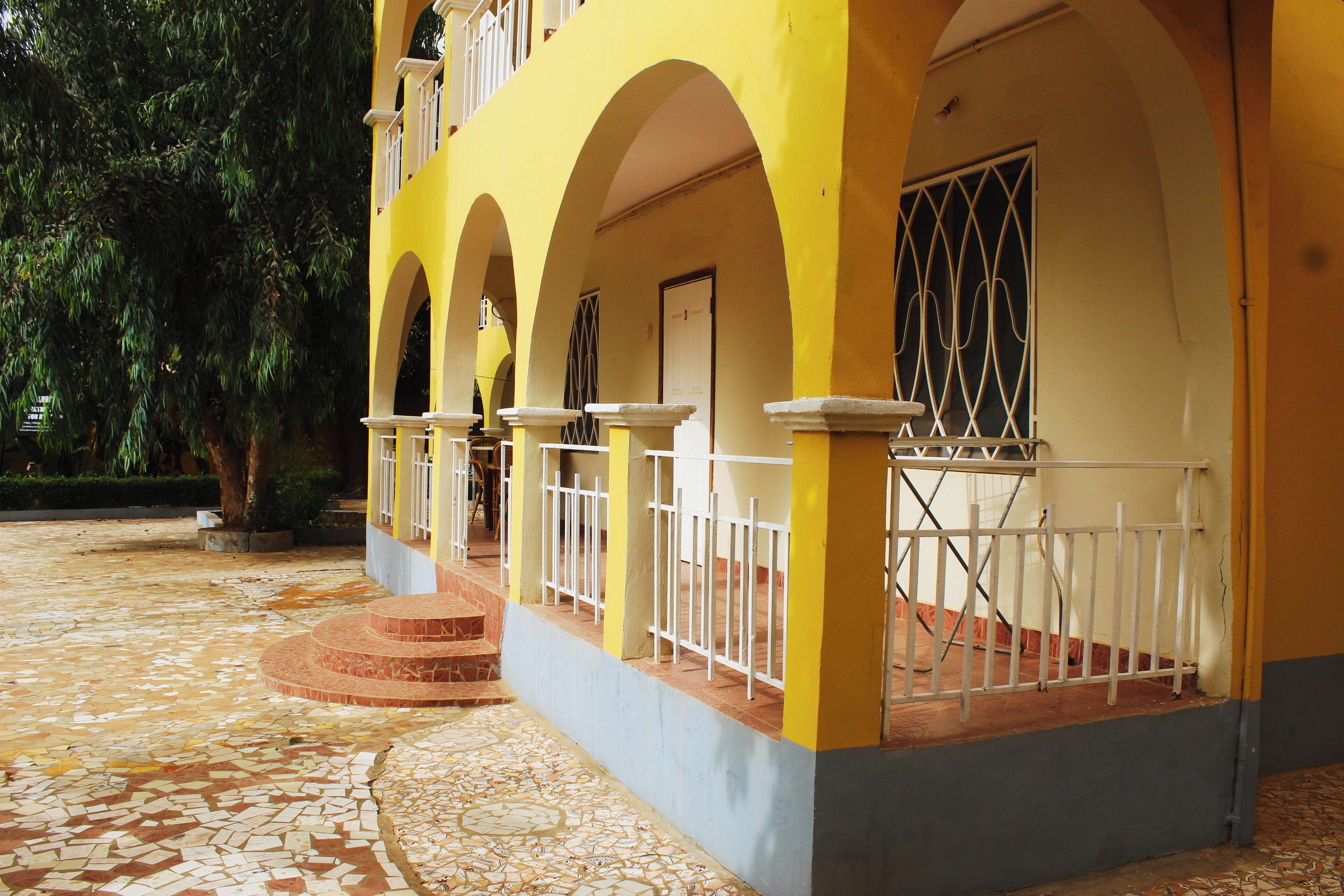A building with yellow and blue exterior walls, white railings, and a tiled floor.