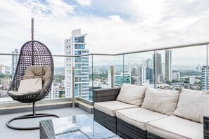 A balcony with a wicker chair and a sofa, offering a city view.